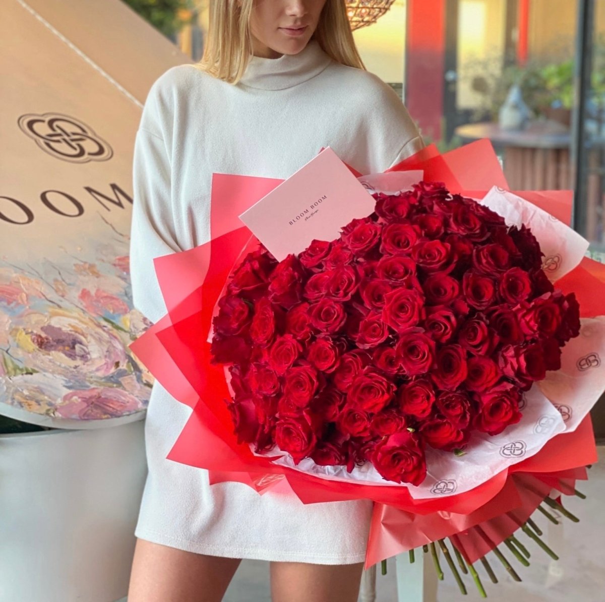 Luxury bouquet of 100 deep red roses wrapped in coral and white paper with branded card