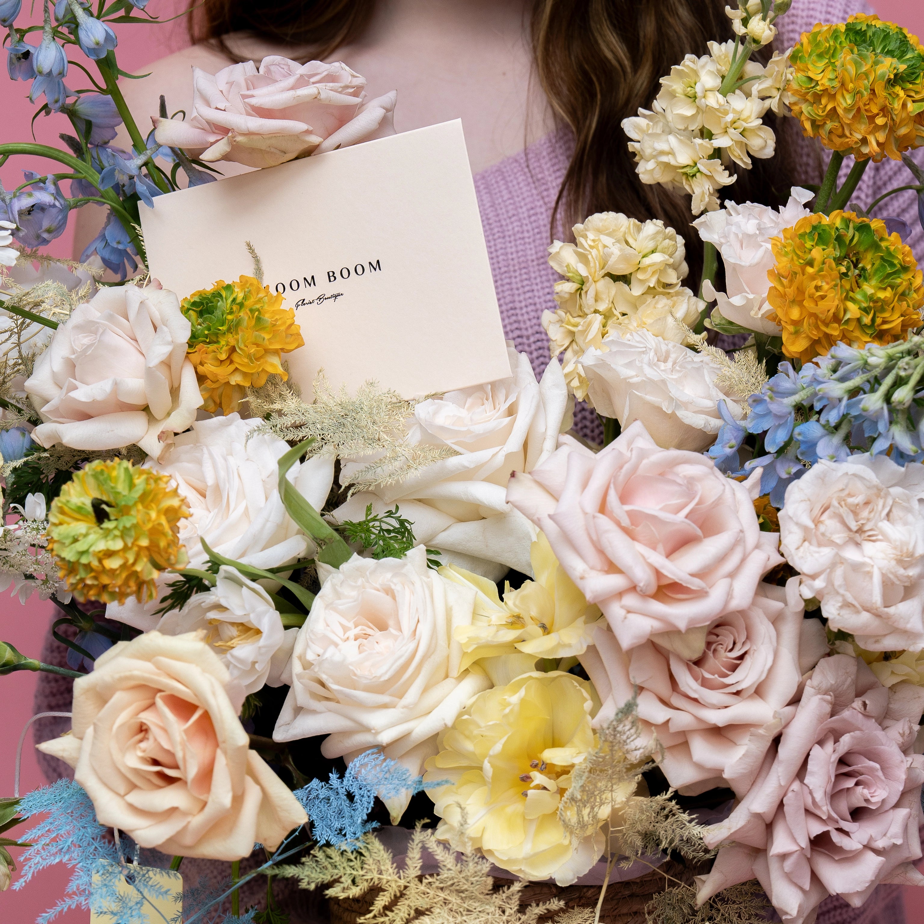 Blush roses, yellow tulips, orange dahlias and blue delphinium flower arrangement with Bloom Boom florist card