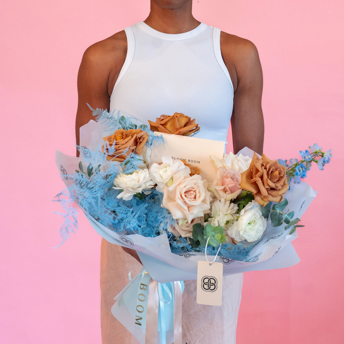 Mixed rose bouquet with blue dusty miller, orange and pink roses, white ranunculus in blue wrapping paper