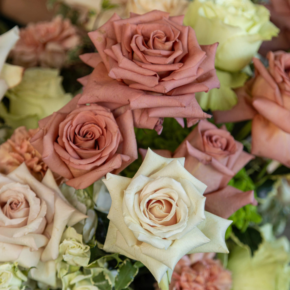 Mixed flower bouquet with dusty rose and cream white roses, pale yellow hydrangea blooms and green foliage