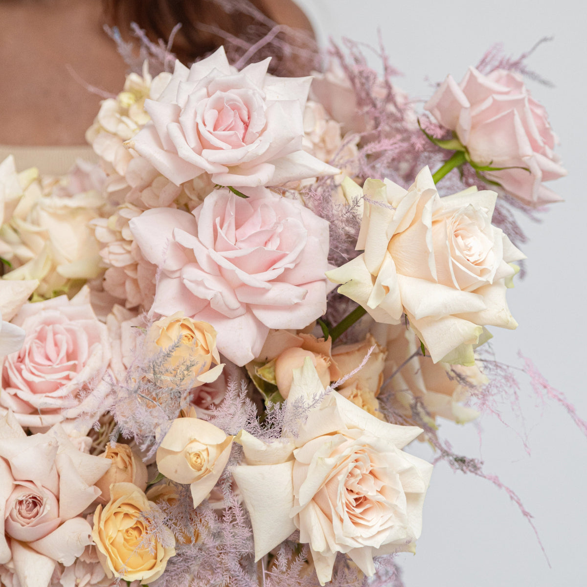 Soft pink and cream roses with dusty miller in elegant bridal bouquet arrangement
