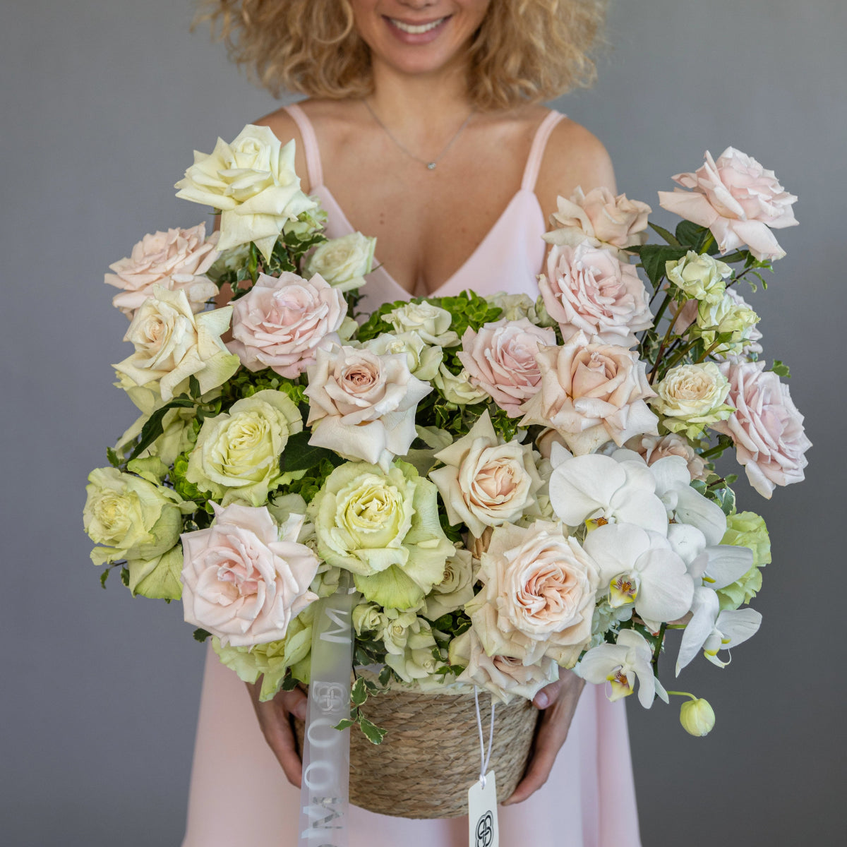 Woven basket flower arrangement with pink, white and green roses, white orchids in natural rope basket