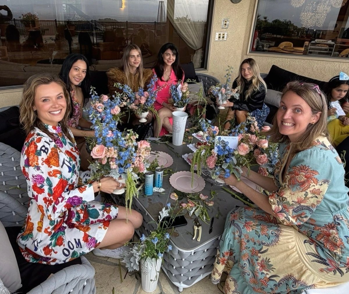 Guests seated around a table with the fresh flower arrangements they created during a Bloom Boom workshop.