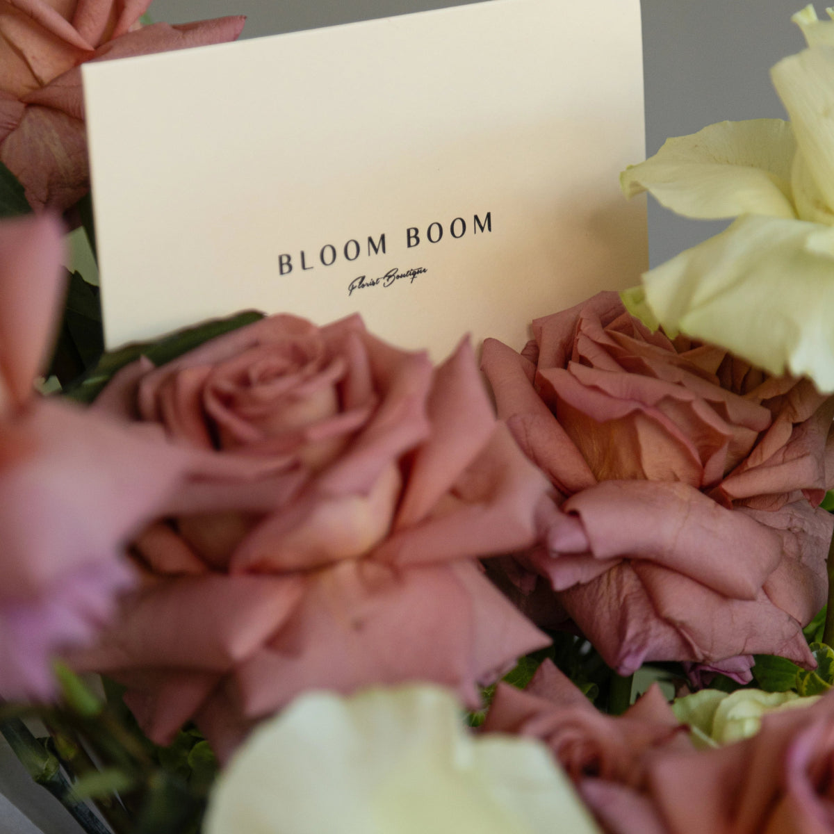 Bloom Boom floral boutique white business card nestled among pink roses and cream colored flowers