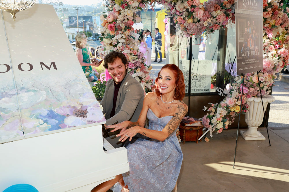 Two guests playing a duet at the white grand piano beneath the floral arch