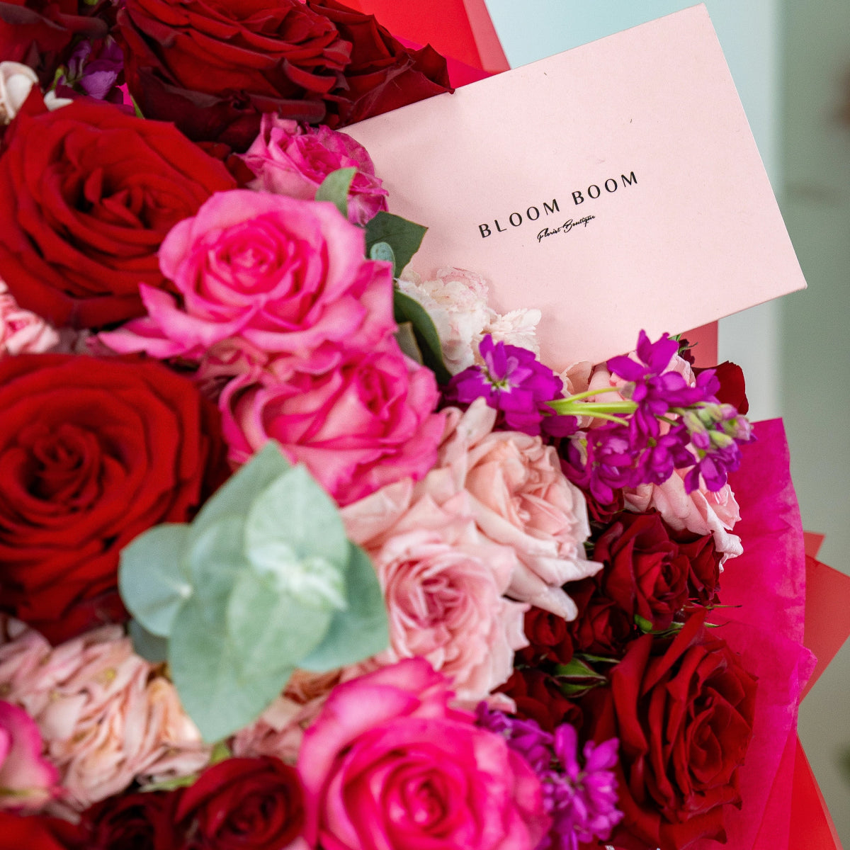 Bloom Boom luxury flower bouquet with red roses, pink roses, purple flowers and eucalyptus with branded card