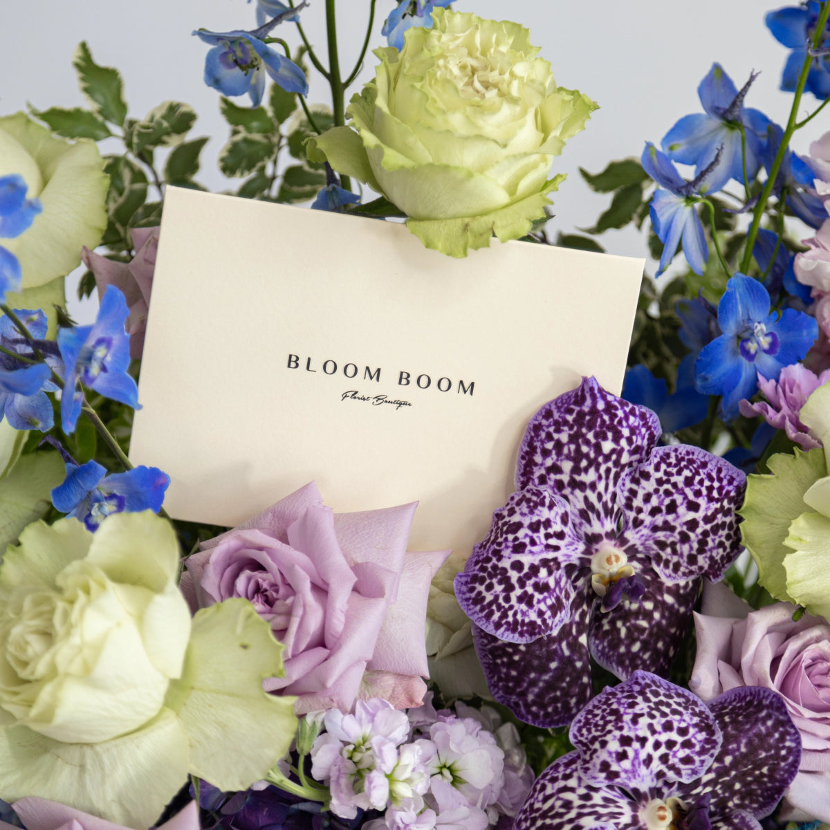 Mixed flower bouquet with purple spotted orchids, lavender roses, lime green roses and blue delphiniums