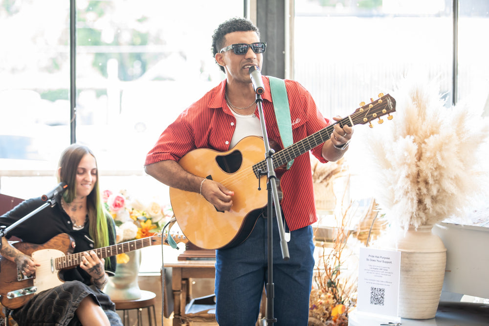 Acoustic duo performing in window light with pampas grass and fresh flowers around them