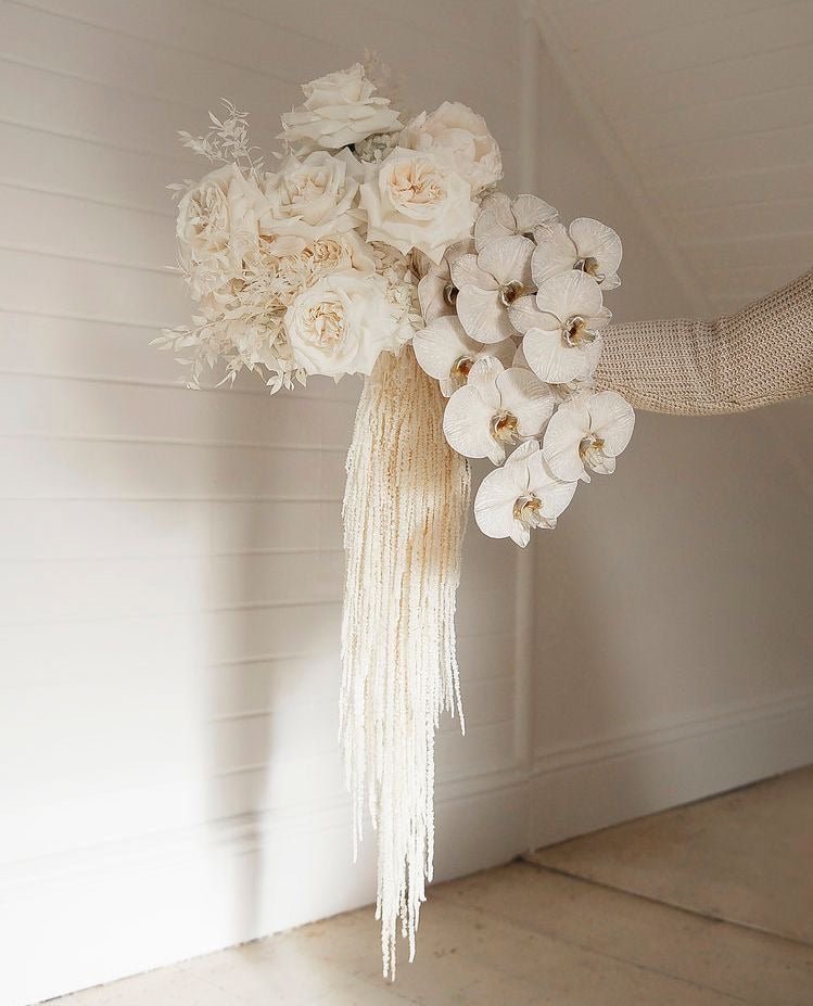 Cream bridal bouquet with white orchids, blush roses, dusty miller and cascading pearl beaded fringe