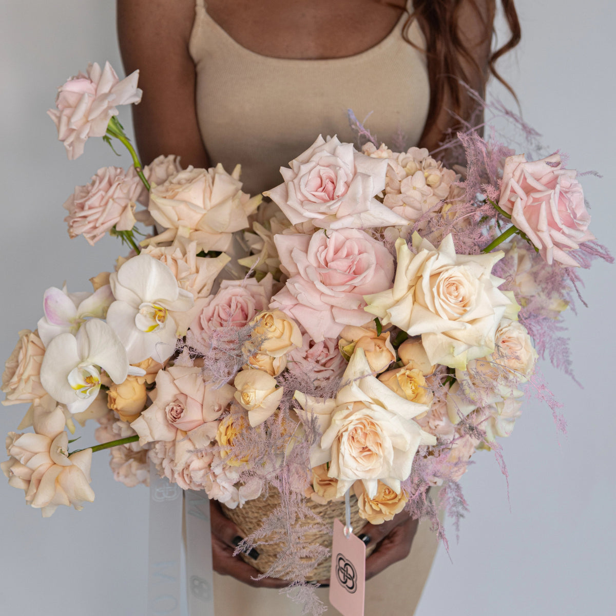 Luxury flower basket with blush pink roses, white orchids and purple dried accents in woven basket