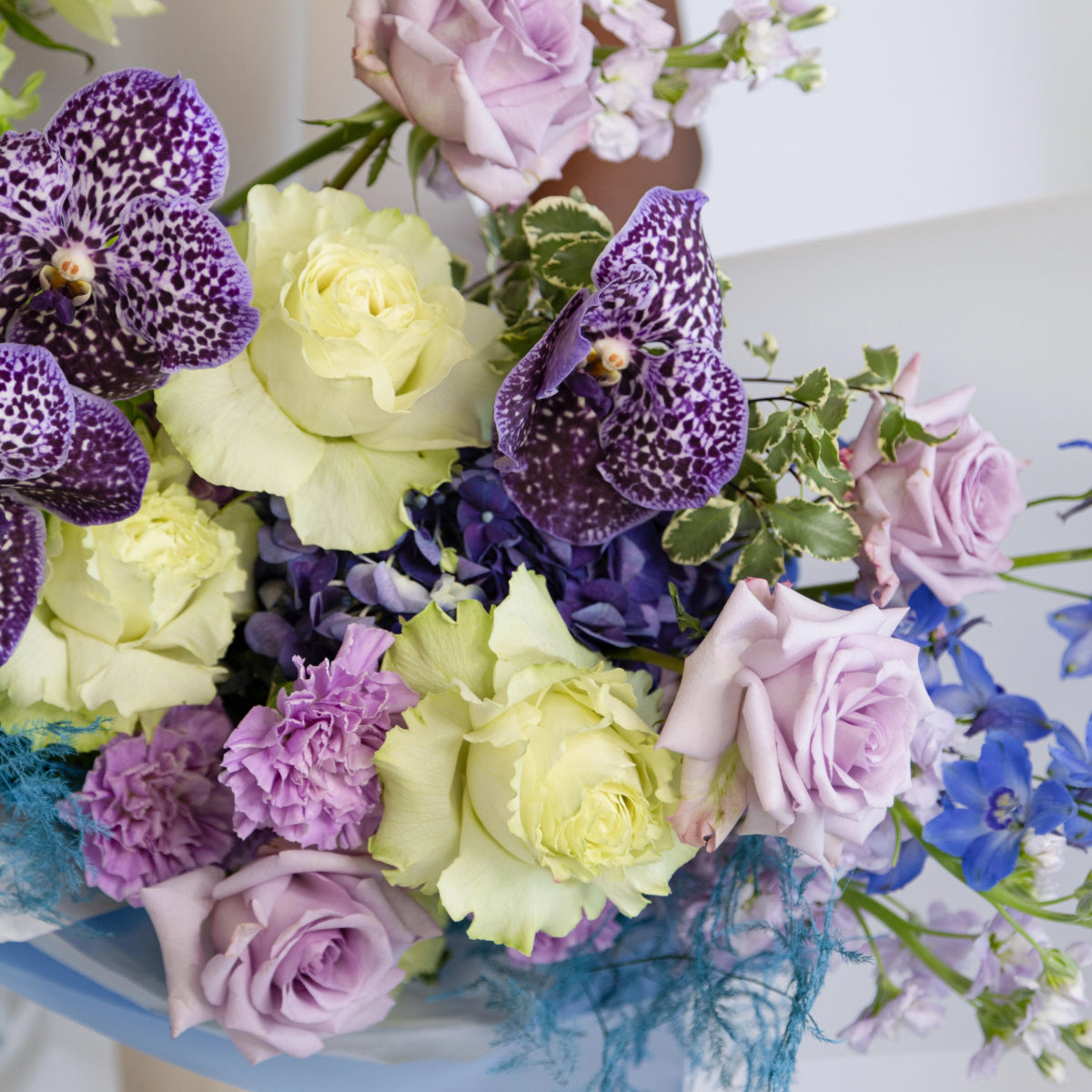 Ocean Breeze bouquet with purple spotted orchids, cream roses, lavender roses, blue hydrangea and teal ribbon