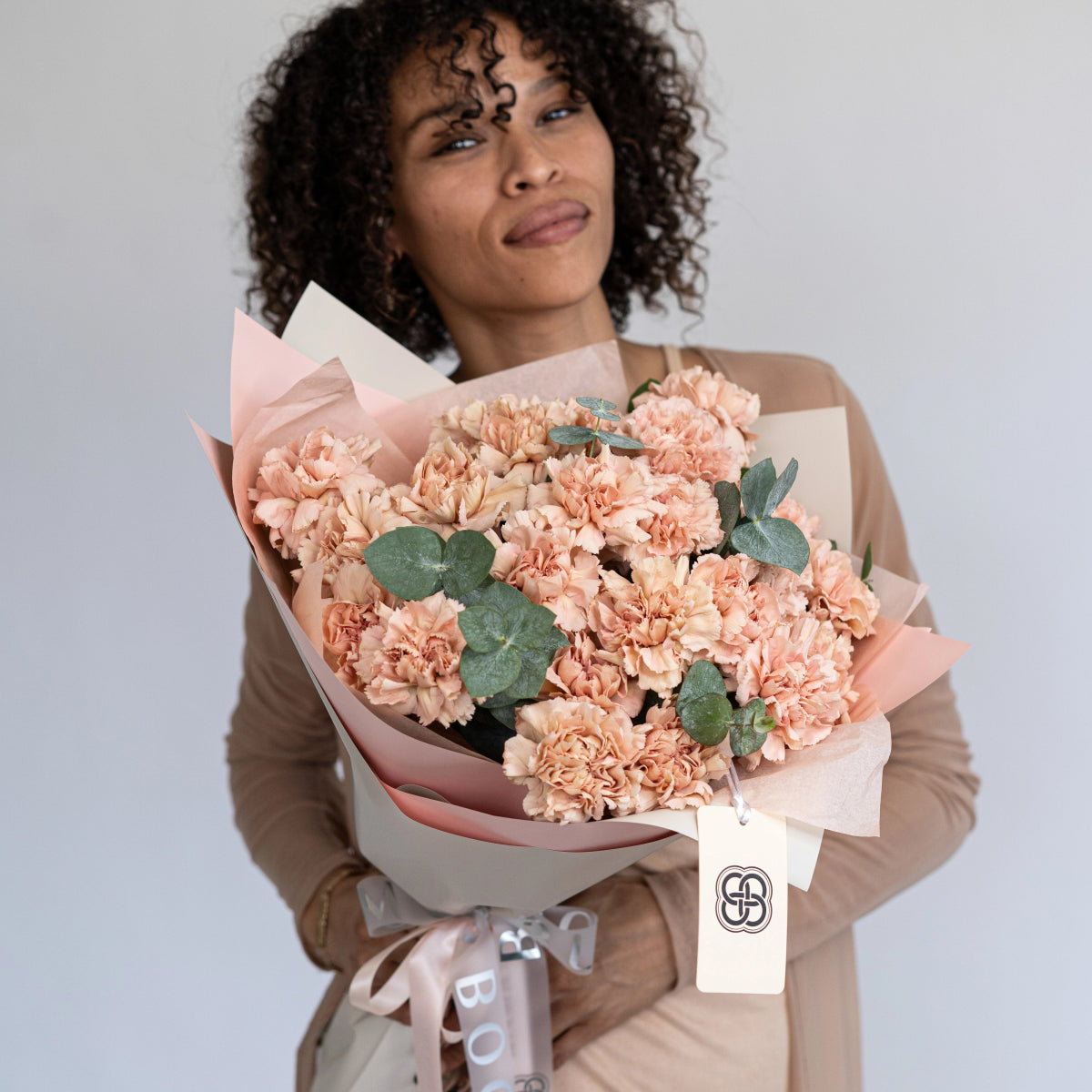 Large peach carnation bouquet with eucalyptus wrapped in pink and cream paper with ribbon