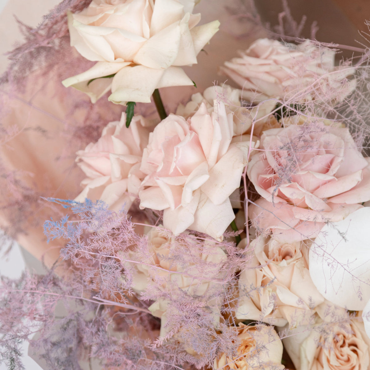 Soft pink and cream rose bouquet with delicate purple dried flowers and wispy decorative elements