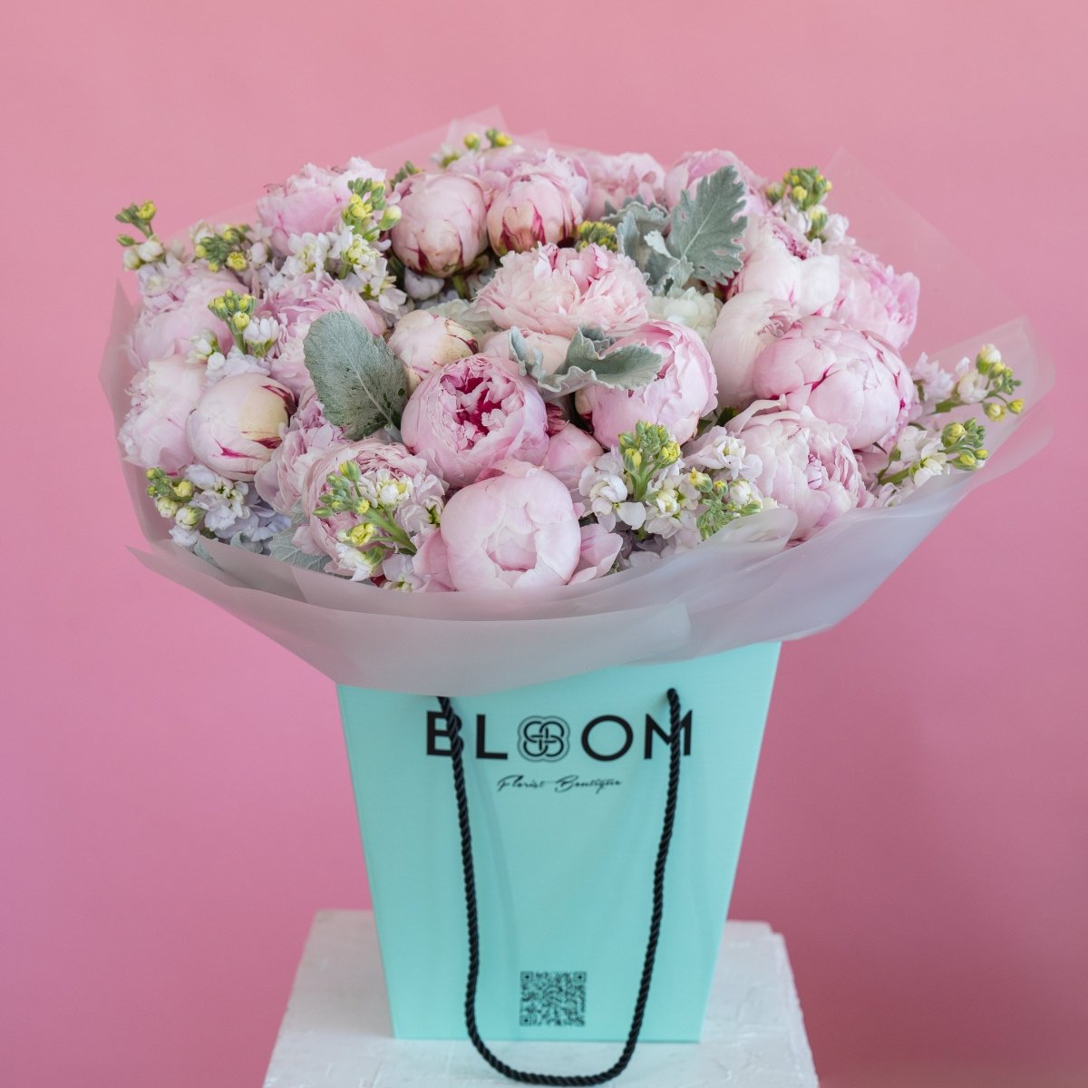Pink peony bouquet with white stock flowers and dusty miller in turquoise Bloom Flower Boutique gift bag