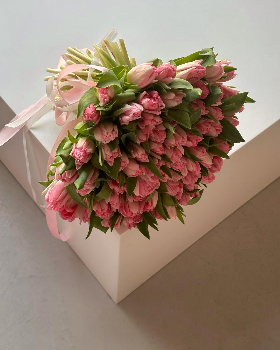 Large bouquet of 75 pink tulips with green leaves tied with pale pink ribbon on white gift box