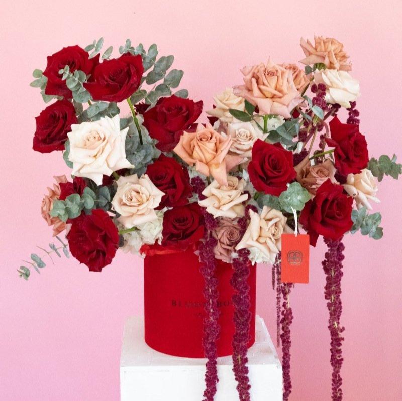 Luxury red velvet flower box with deep red and blush pink roses, eucalyptus, and cascading purple amaranthus