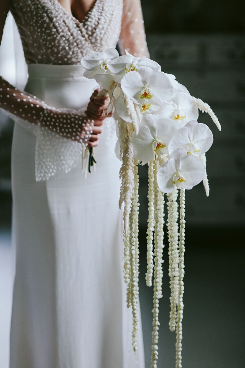 White orchid bridal bouquet with cascading pearl amaranth tails and lace ribbon wrap