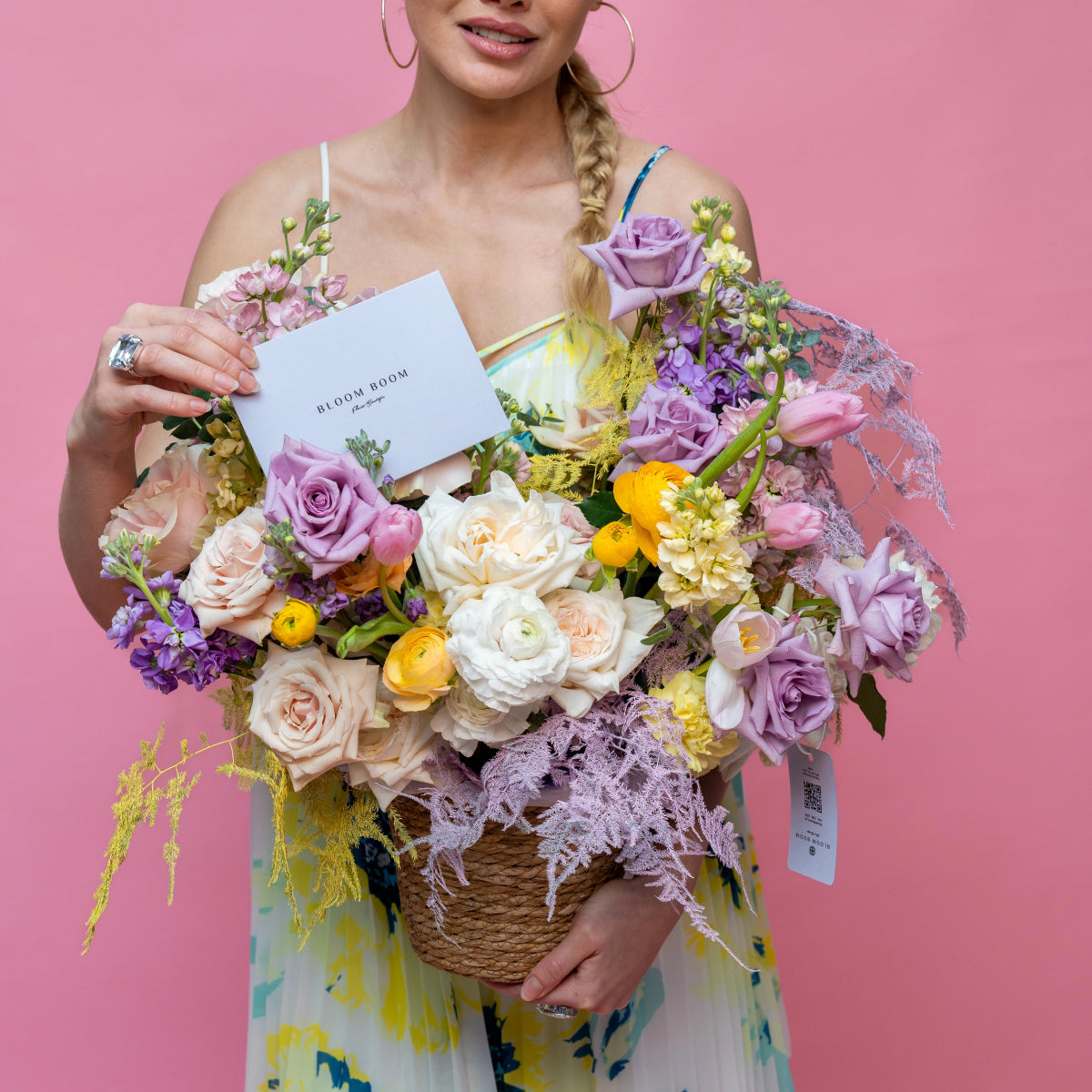 Wicker basket bouquet with purple roses, white ranunculus, yellow flowers and dusty miller in rope basket